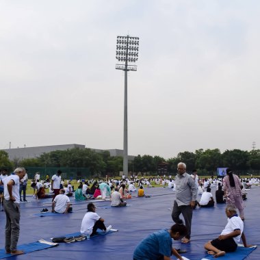 Yeni Delhi, Hindistan, 21 Haziran 2023 - Uluslararası Yoga Günü 'nde Delhi' deki Yamuna Spor Kompleksi 'nde grup Yoga egzersiz oturumu, kriket stadyumunda yoga derslerine katılan büyük bir grup yetişkin