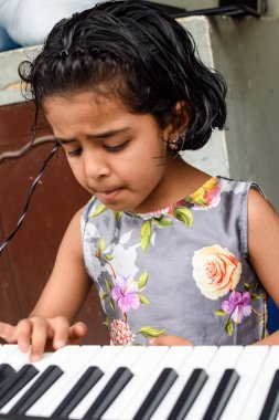 Sentezleyici ya da piyano çalan Asyalı tatlı kız. Küçük şirin çocuk piyano çalmayı öğreniyor. Çocuk elleri klavyenin içinde..