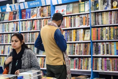 Delhi, Hindistan, 17 Şubat 2024 - Çeşitli yaş gruplarından insanlar Delhi Uluslararası Kitap Fuarı 'ndaki bir kitapçıda çeşitli kitaplar okuyor, Bharat Mandapam kompleksindeki Yıllık Kitap Fuarı' nda kitaplar