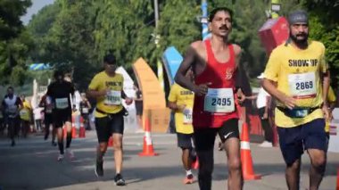 Yeni Delhi, Hindistan - 15 Ekim 2023 - Bitmek üzere olan maraton katılımcılarının bitiş çizgisini geçmek üzere olan Delhi Yarı Maratonu 2023