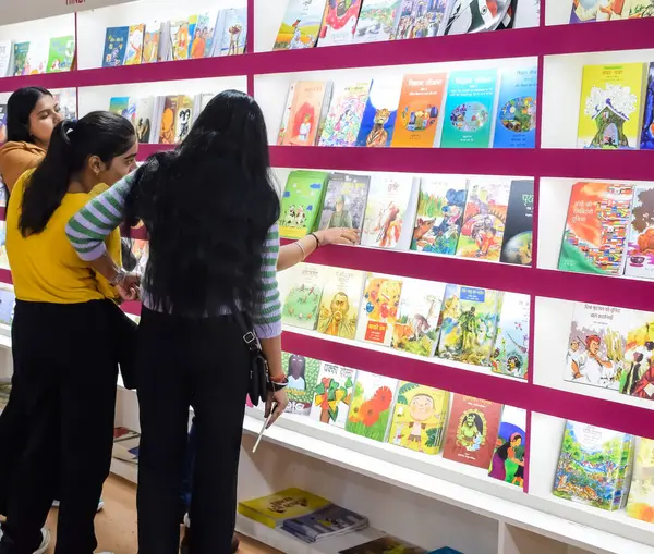 stock image Delhi, India, February 17 2024 - Various age group people reading variety of Books on shelf inside a book-stall at Delhi International Book Fair, Books in Annual Book Fair at Bharat Mandapam complex