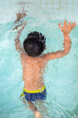Havuzda yüzen mutlu Hintli çocuk, sıcak yaz tatillerinde hava tüpüyle birlikte yüzen çocuk, büyük bir havuzda yüzen çocuk..