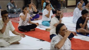 Yeni Delhi, Hindistan, 19 Nisan 2024 - Balaji Tapınağı, Vivek Vihar, Uluslararası Yoga Günü, tapınaktaki yoga sınıfına katılan büyük bir grup yetişkin için grup yoga oturumu
