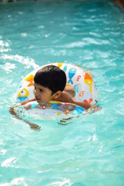 Havuzda yüzen mutlu Hintli çocuk, sıcak yaz tatillerinde hava tüpüyle birlikte yüzen çocuk, büyük bir havuzda yüzen çocuk..