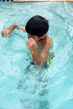 Havuzda yüzen mutlu Hintli çocuk, sıcak yaz tatillerinde hava tüpüyle birlikte yüzen çocuk, büyük bir havuzda yüzen çocuk..