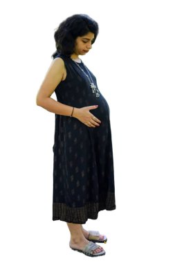 Hamile bir Hintli kadın hamilelik çekimi için poz veriyor ve elleri beyaz arka planda, Hintli hamile kadın elini karnının üstüne koyuyor.