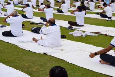 Yeni Delhi, Hindistan, 21 Haziran 2023 - Uluslararası Yoga Günü 'nde Delhi' deki Yamuna Spor Kompleksi 'nde grup Yoga egzersiz oturumu, kriket stadyumunda yoga derslerine katılan büyük bir grup yetişkin