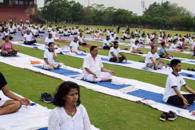 Yeni Delhi, Hindistan, 21 Haziran 2023 - Uluslararası Yoga Günü 'nde Delhi' deki Yamuna Spor Kompleksi 'nde grup Yoga egzersiz oturumu, kriket stadyumunda yoga derslerine katılan büyük bir grup yetişkin
