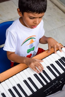 Sentezleyici ya da piyano çalan Asyalı çocuk. Küçük şirin çocuk piyano çalmayı öğreniyor. Çocuk elleri klavyenin içinde..