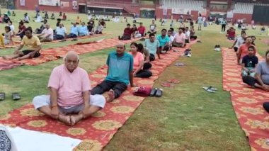 Yeni Delhi, Hindistan, 21 Haziran 2024 - Uluslararası Yoga Günü 'nde Delhi' deki Yamuna Spor Kompleksi 'nde grup Yoga egzersiz oturumu, kriket stadyumunda yoga sınıfına katılan büyük bir grup yetişkin