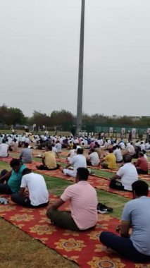 Yeni Delhi, Hindistan, 21 Haziran 2024 - Uluslararası Yoga Günü 'nde Delhi' deki Yamuna Spor Kompleksi 'nde grup Yoga egzersiz oturumu, kriket stadyumunda yoga sınıfına katılan büyük bir grup yetişkin