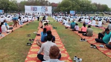 Yeni Delhi, Hindistan, 21 Haziran 2024 - Uluslararası Yoga Günü 'nde Delhi' deki Yamuna Spor Kompleksi 'nde grup Yoga egzersiz oturumu, kriket stadyumunda yoga sınıfına katılan büyük bir grup yetişkin