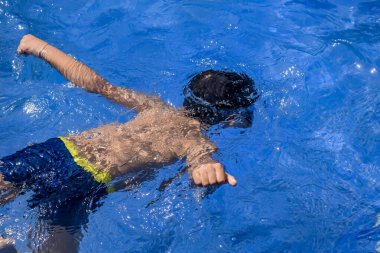 Havuzda yüzen mutlu Hintli çocuk, sıcak yaz tatillerinde hava tüpüyle birlikte yüzen çocuk, büyük bir havuzda yüzen çocuk..