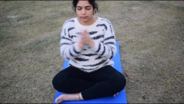 Young Indian woman practicing yoga outdoor in a park. Beautiful girl practice basic yoga pose. Calmness and relax, female happiness. Basic Yoga poses outdoor 