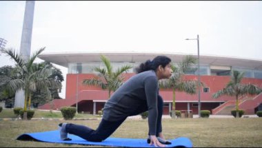 Young Indian woman practicing yoga outdoor in a park. Beautiful girl practice basic yoga pose. Calmness and relax, female happiness. Basic Yoga poses outdoor 