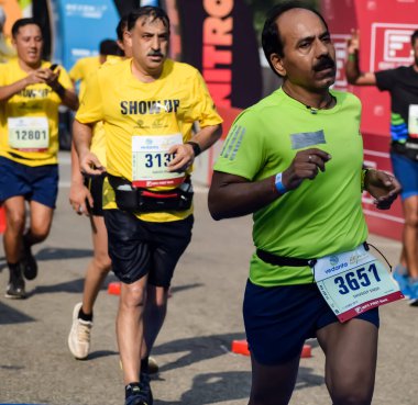 Yeni Delhi, Hindistan - 15 Ekim 2023 - Bitmek üzere olan maraton katılımcılarının bitiş çizgisini geçmek üzere olan Delhi Yarı Maratonu 2023