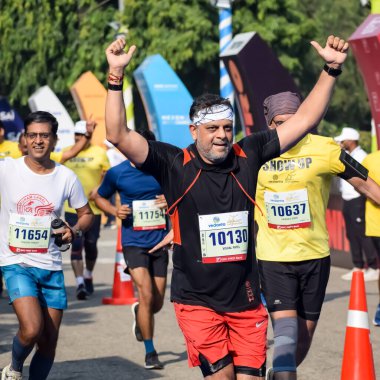 Yeni Delhi, Hindistan - 15 Ekim 2023 - Bitmek üzere olan maraton katılımcılarının bitiş çizgisini geçmek üzere olan Delhi Yarı Maratonu 2023