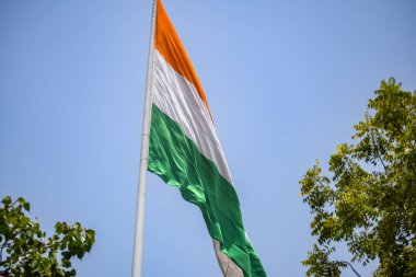 India flag flying high at Connaught Place with pride in blue sky, India flag fluttering, Indian Flag on Independence Day and Republic Day of India, tilt up shot, Waving Indian flag, Har Ghar Tiranga