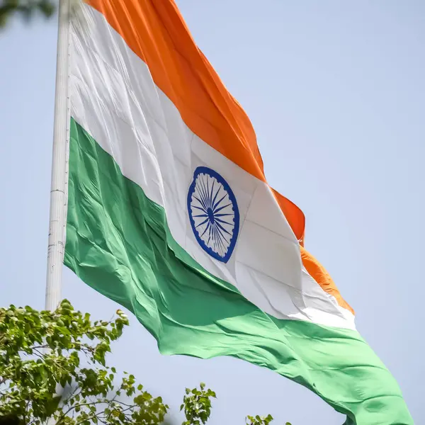 stock image India flag flying high at Connaught Place with pride in blue sky, India flag fluttering, Indian Flag on Independence Day and Republic Day of India, tilt up shot, Waving Indian flag, Har Ghar Tiranga