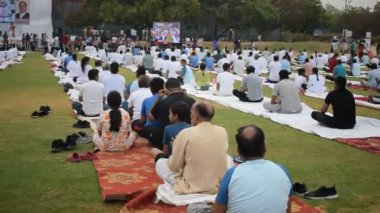 Yeni Delhi, Hindistan, 21 Haziran 2024 - Uluslararası Yoga Günü 'nde Delhi' deki Yamuna Spor Kompleksi 'nde grup Yoga egzersiz oturumu, kriket stadyumunda yoga sınıfına katılan büyük bir grup yetişkin