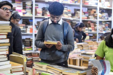 Delhi, Hindistan, 17 Şubat 2024 - Çeşitli yaş gruplarından insanlar Delhi Uluslararası Kitap Fuarı 'ndaki bir kitapçıda çeşitli kitaplar okuyor, Bharat Mandapam kompleksindeki Yıllık Kitap Fuarı' nda kitaplar