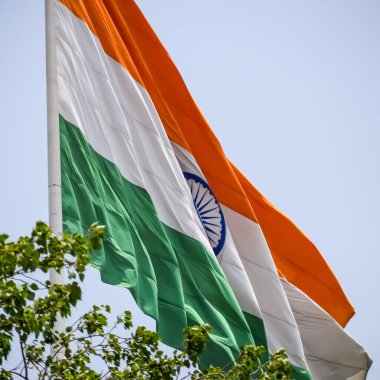 India flag flying high at Connaught Place with pride in blue sky, India flag fluttering, Indian Flag on Independence Day and Republic Day of India, tilt up shot, Waving Indian flag, Har Ghar Tiranga