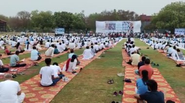 Yeni Delhi, Hindistan, 21 Haziran 2024 - Uluslararası Yoga Günü 'nde Delhi' deki Yamuna Spor Kompleksi 'nde grup Yoga egzersiz oturumu, kriket stadyumunda yoga sınıfına katılan büyük bir grup yetişkin