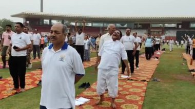 Yeni Delhi, Hindistan, 21 Haziran 2024 - Uluslararası Yoga Günü 'nde Delhi' deki Yamuna Spor Kompleksi 'nde grup Yoga egzersiz oturumu, kriket stadyumunda yoga sınıfına katılan büyük bir grup yetişkin