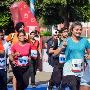 Yeni Delhi, Hindistan - 15 Ekim 2023 - Bitmek üzere olan maraton katılımcılarının bitiş çizgisini geçmek üzere olan Delhi Yarı Maratonu 2023