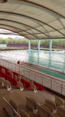 Yeni Delhi, Hindistan, 12 Temmuz 2024 - Kimliği belirlenemeyen bir grup insan büyük yüzme havuzunda yüzme koçluğu yapıyor, farklı yaş gruplarından insanlar spor kompleksindeki büyük yüzme havuzunda