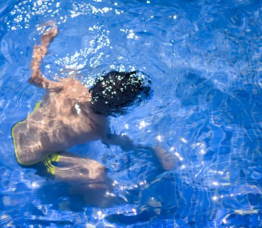 Havuzda yüzen mutlu Hintli çocuk, sıcak yaz tatillerinde hava tüpüyle birlikte yüzen çocuk, büyük bir havuzda yüzen çocuk..