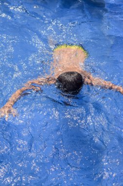 Havuzda yüzen mutlu Hintli çocuk, sıcak yaz tatillerinde hava tüpüyle birlikte yüzen çocuk, büyük bir havuzda yüzen çocuk..