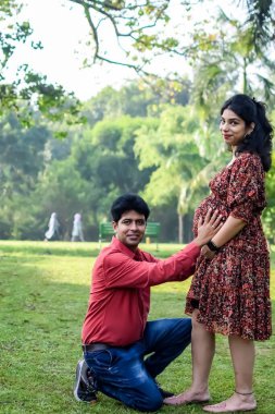 Hintli çift doğum çekimi için poz veriyor. Delhi 'deki Lodhi Garden' da yeni doğan bebeğe kucak açıyorlar. Anne ve babalar çocuklarını karşıladıkları için annelik fotoğrafı çekiyorlar.