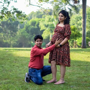 Hintli çift doğum çekimi için poz veriyor. Delhi 'deki Lodhi Garden' da yeni doğan bebeğe kucak açıyorlar. Anne ve babalar çocuklarını karşıladıkları için annelik fotoğrafı çekiyorlar.