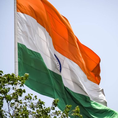 India flag flying high at Connaught Place with pride in blue sky, India flag fluttering, Indian Flag on Independence Day and Republic Day of India, tilt up shot, Waving Indian flag, Har Ghar Tiranga
