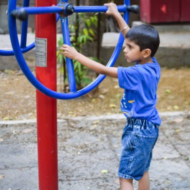 Asyalı çocuk sabah vakti sosyete parkında rutin egzersiz yapıyor. Kendini hayat boyu zinde tutmak için şirin bir çocuk egzersizi ve spor salonu. Açık havada çocuk egzersizi.