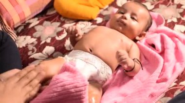 10 aylık anne, evde yağ masajı yapan sevimli küçük Hintli çocuk, yağ masajının tadını çıkaran küçük sevimli çocuk, küçük bebek anne tarafından sağlıklı bir masajın keyfini çıkarıyor.