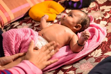 10 aylık sevimli Hintli çocuk evde annesine yağ masajı yapıyor, küçük tatlı çocuk yağ masajının tadını çıkarıyor, küçük çocuk annesinin sağlıklı masajının keyfini çıkarıyor.