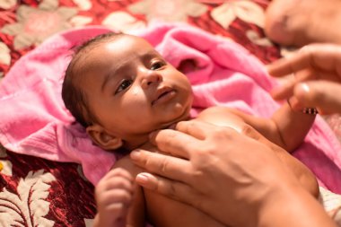 10 aylık sevimli Hintli çocuk evde annesine yağ masajı yapıyor, küçük tatlı çocuk yağ masajının tadını çıkarıyor, küçük çocuk annesinin sağlıklı masajının keyfini çıkarıyor.