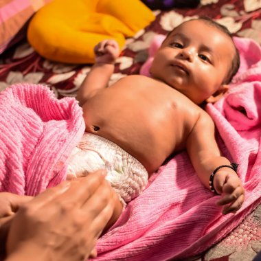 10 aylık sevimli Hintli çocuk evde annesine yağ masajı yapıyor, küçük tatlı çocuk yağ masajının tadını çıkarıyor, küçük çocuk annesinin sağlıklı masajının keyfini çıkarıyor.