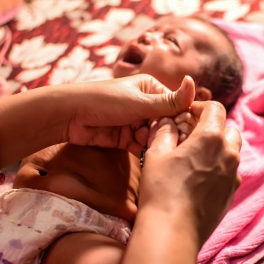 10 aylık sevimli Hintli çocuk evde annesine yağ masajı yapıyor, küçük tatlı çocuk yağ masajının tadını çıkarıyor, küçük çocuk annesinin sağlıklı masajının keyfini çıkarıyor.