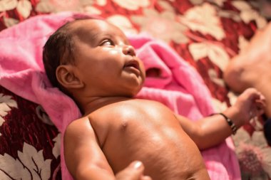 10 aylık sevimli Hintli çocuk evde annesine yağ masajı yapıyor, küçük tatlı çocuk yağ masajının tadını çıkarıyor, küçük çocuk annesinin sağlıklı masajının keyfini çıkarıyor.