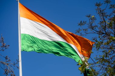 India flag flying high at Connaught Place with pride in blue sky, India flag fluttering, Indian Flag on Independence Day and Republic Day of India, tilt up shot, Waving Indian flag, Har Ghar Tiranga