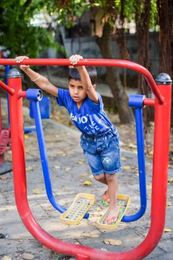 Asyalı çocuk sabah vakti sosyete parkında rutin egzersiz yapıyor. Kendini hayat boyu zinde tutmak için şirin bir çocuk egzersizi ve spor salonu. Açık havada çocuk egzersizi.