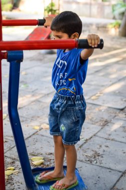 Asyalı çocuk sabah vakti sosyete parkında rutin egzersiz yapıyor. Kendini hayat boyu zinde tutmak için şirin bir çocuk egzersizi ve spor salonu. Açık havada çocuk egzersizi.