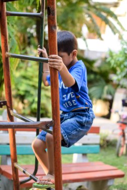 Asyalı çocuk sabah vakti sosyete parkında rutin egzersiz yapıyor. Kendini hayat boyu zinde tutmak için şirin bir çocuk egzersizi ve spor salonu. Açık havada çocuk egzersizi.