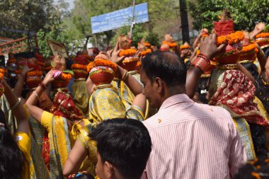 New Delhi, India July 25 2024 - Women with Kalash on head during Jagannath Temple Mangal Kalash Yatra, Indian Hindu devotees carry earthen pots containing sacred water with a coconut on top clipart