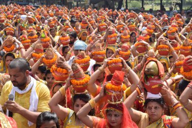 New Delhi, India July 25 2024 - Women with Kalash on head during Jagannath Temple Mangal Kalash Yatra, Indian Hindu devotees carry earthen pots containing sacred water with a coconut on top clipart