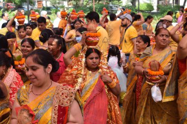 New Delhi, India July 25 2024 - Women with Kalash on head during Jagannath Temple Mangal Kalash Yatra, Indian Hindu devotees carry earthen pots containing sacred water with a coconut on top clipart