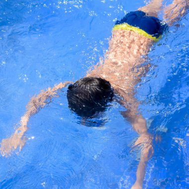 Havuzda yüzen mutlu Hintli çocuk, sıcak yaz tatillerinde hava tüpüyle birlikte yüzen çocuk, büyük bir havuzda yüzen çocuk..